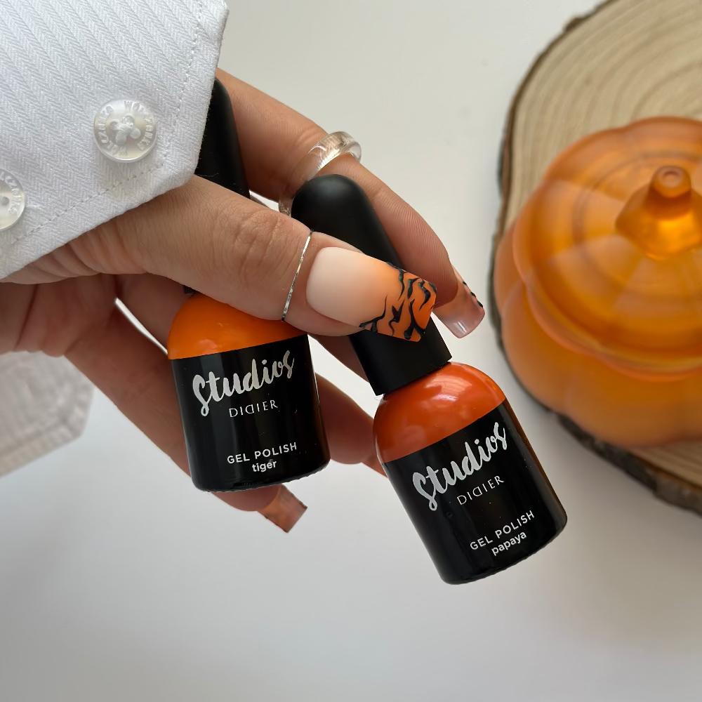 Hand holding two bottles of Studio's gel polish with a white background