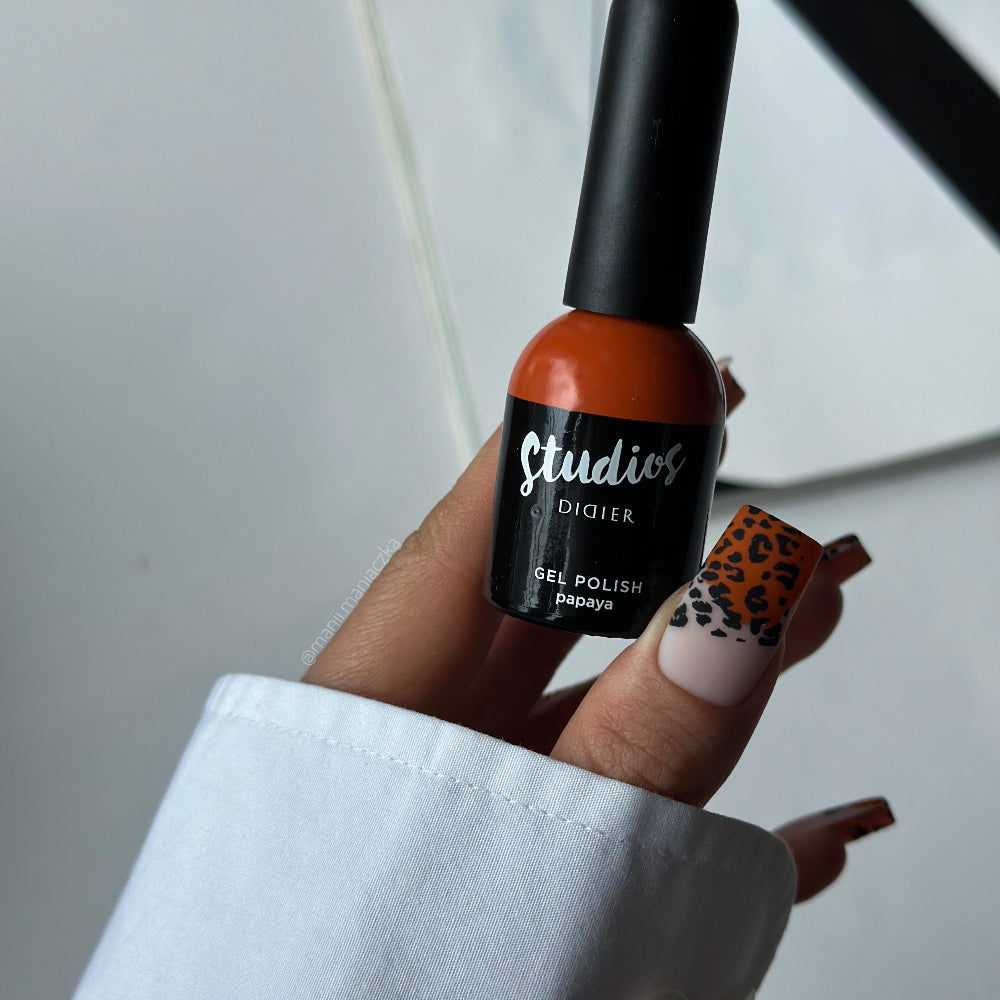 Hand holding a bottle of Studio's gel polish with a white background